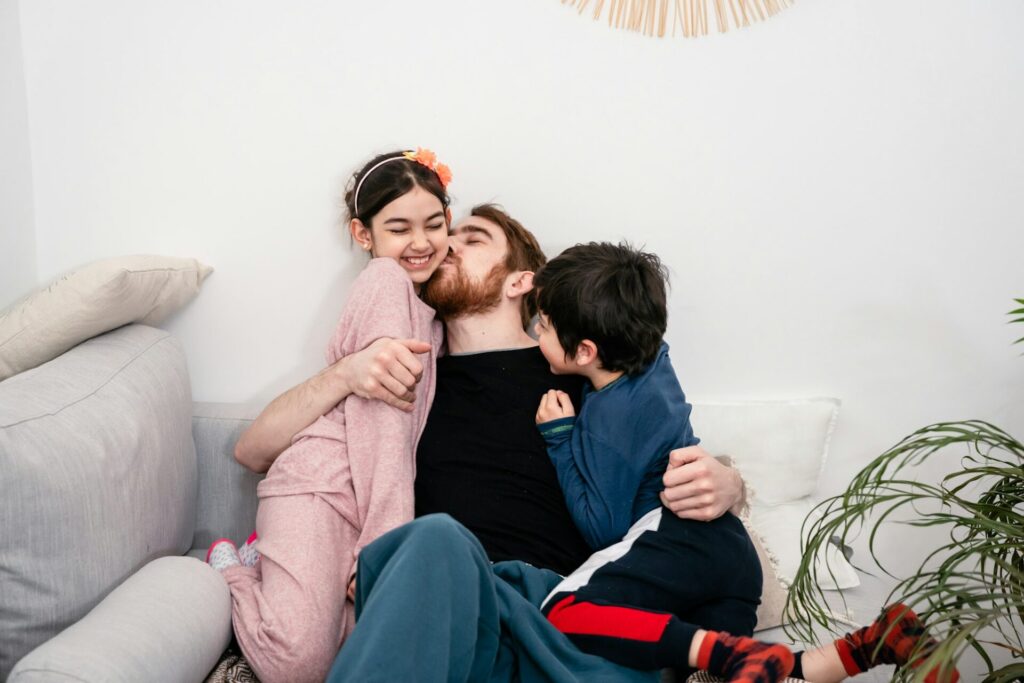 Father and two kids embracing on sofa at home